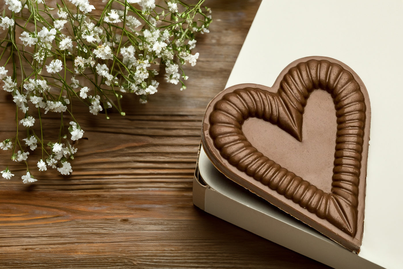 chocolate wedding favors chocolate molded heart on table next to white flowers stefanelli's candies