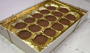 Box of milk chocolate meltawys with gold wrapping on a white surface
