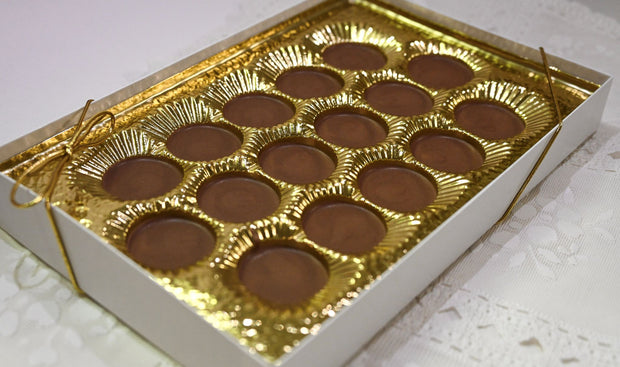 Box of milk chocolate meltawys with gold wrapping on a white surface